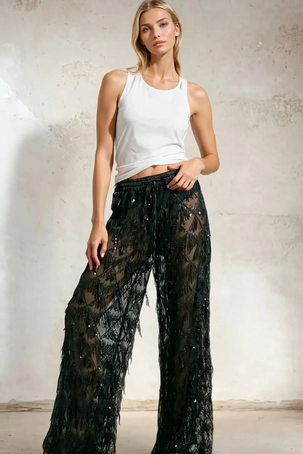 Modelo feminina usando calça preta transparente em tule bordado com lantejoulas, cintura alta. Uma peça que une conforto, elegância e brilho na medida certa. Nossa calça preta em tule com lantejoulas é perfeita para eventos noturnos com estilo marcante.