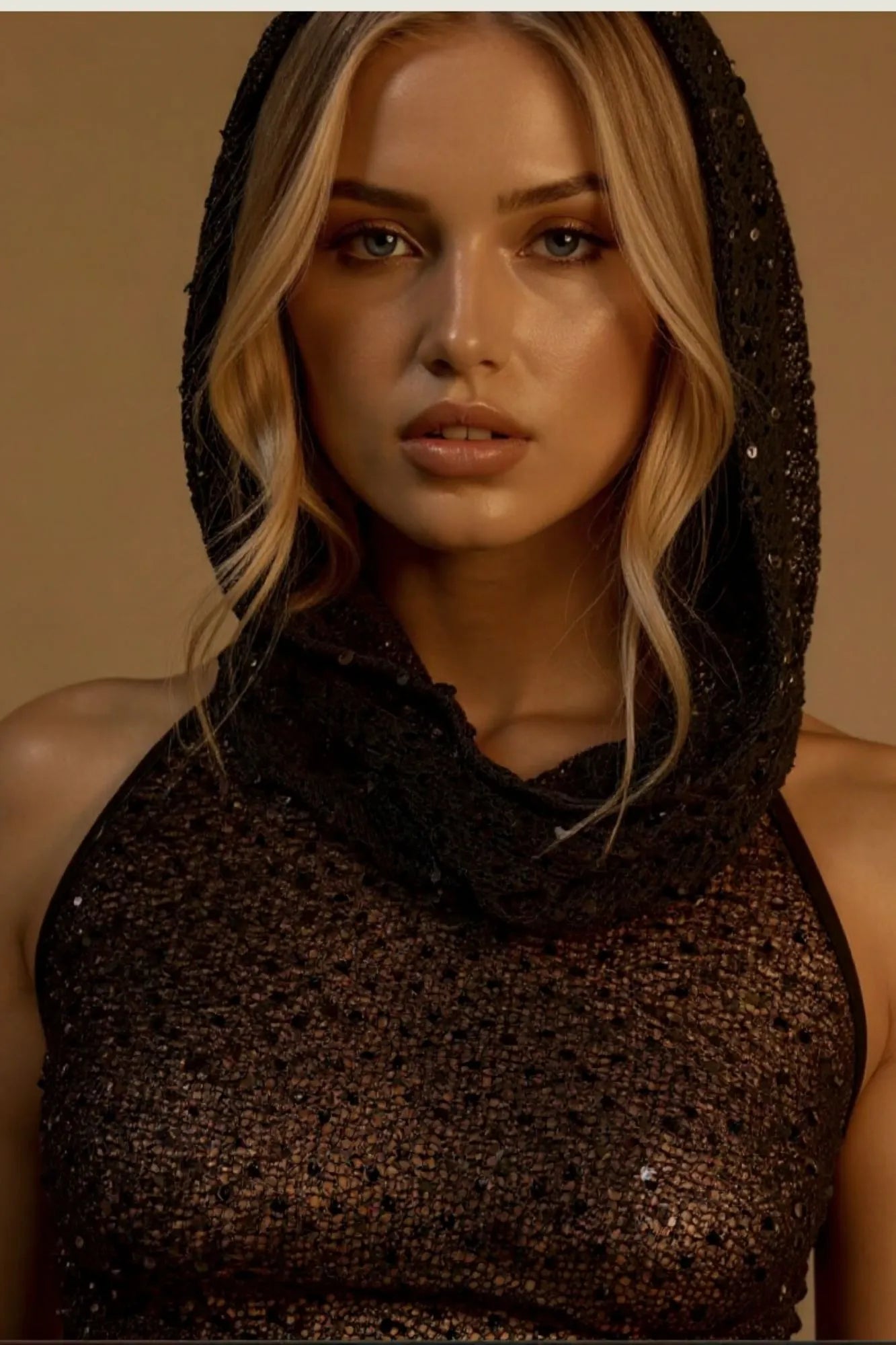 Modelo feminina vestindo top preto frente única em paetê com capuz e ajuste nas costas. Paetês, estilo e um capuz que faz toda a diferença. Esse top preto frente única é a definição de um visual marcante e exclusivo para arrasar nas noites especiais.