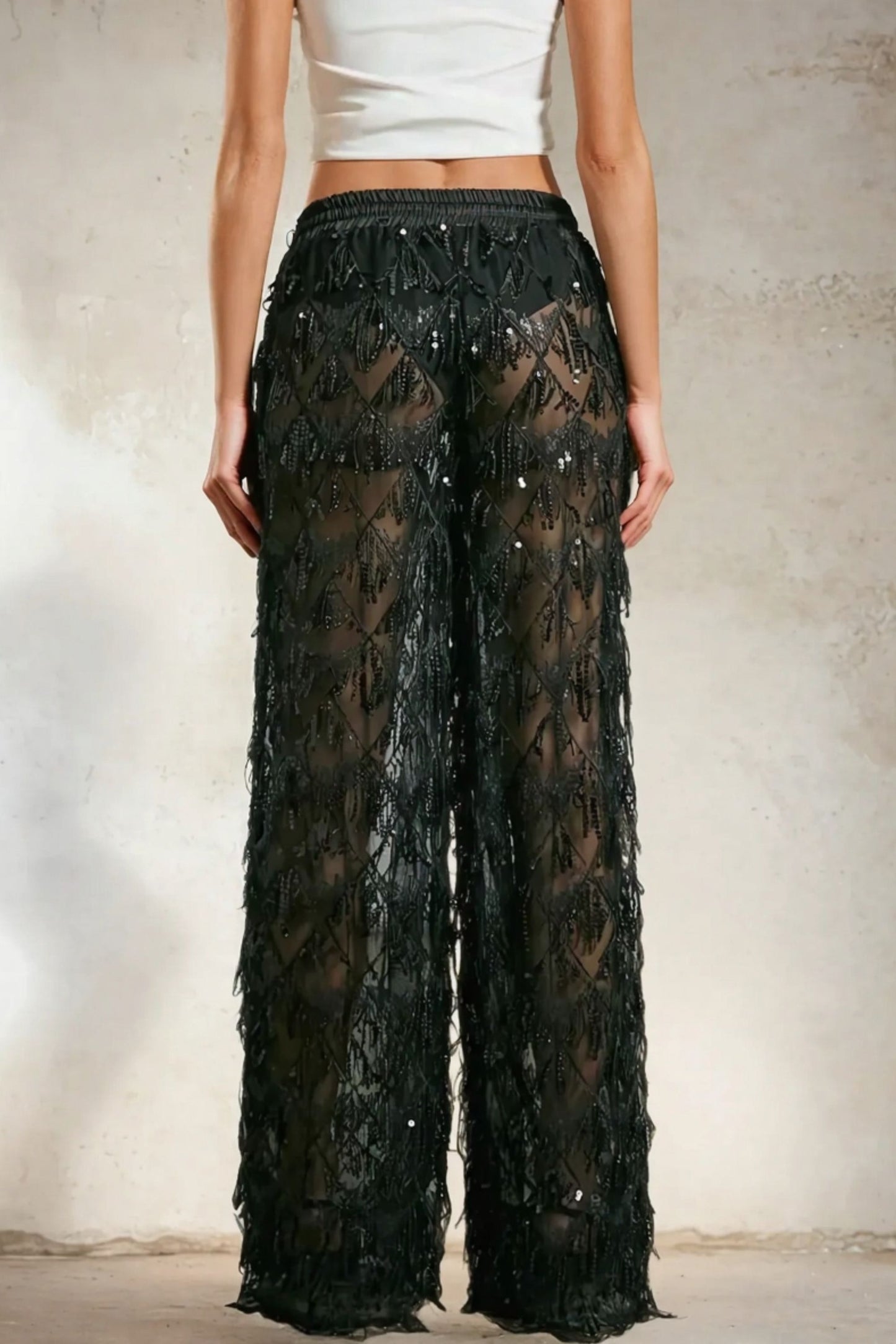 Modelo feminina usando calça preta transparente em tule bordado com lantejoulas, cintura alta. Uma peça que une conforto, elegância e brilho na medida certa. Nossa calça preta em tule com lantejoulas é perfeita para eventos noturnos com estilo marcante.